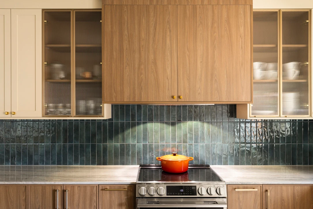 Kitchen range wall with ribbed glass cabinets, walnut upper cabinet and teal tile backsplash