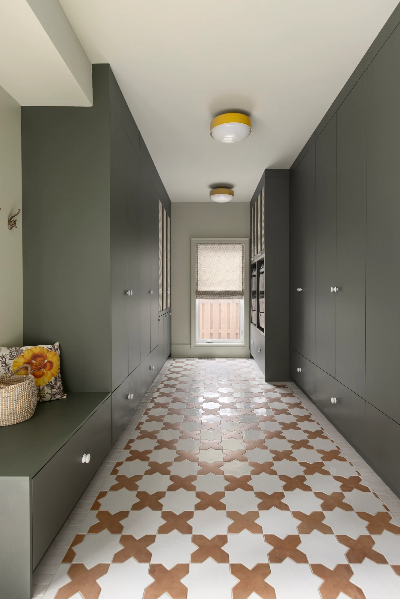 Olive green mudroom cabinetry with a storage bench and a patterned cross-shaped tile floor
