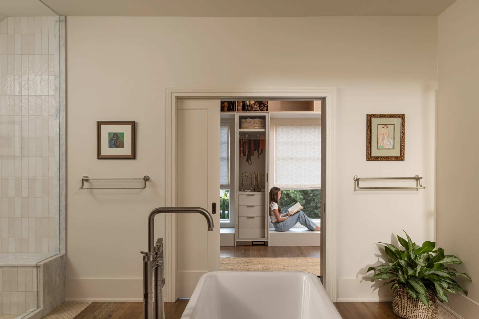 Bathroom with a freestanding tub and a pocket door opening to a walk-in closet with built-in storage