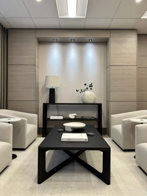 Wood-panelled lounge wall with a recessed niche, a black coffee table and cream armchairs