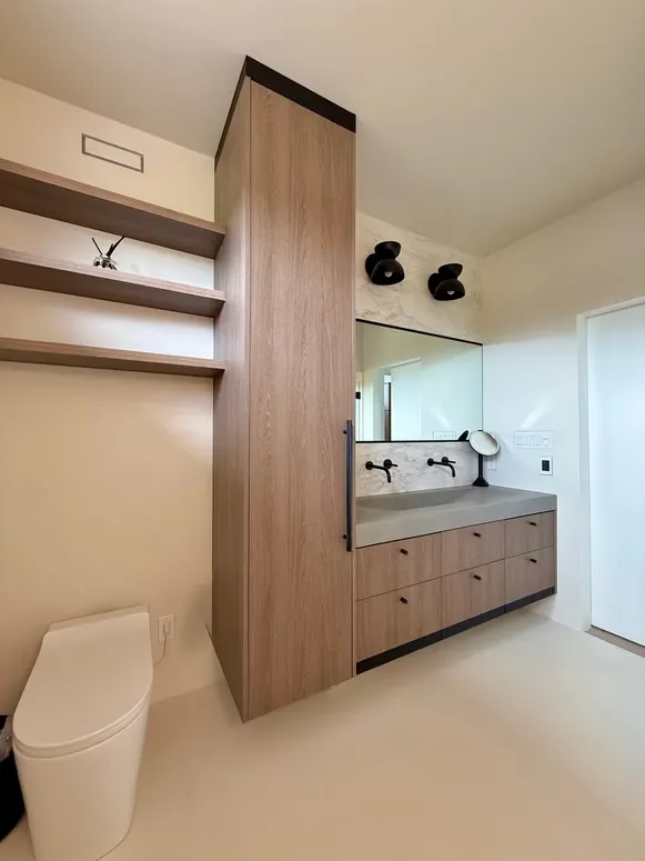 Bathroom with a tall wood-grain storage tower, open shelves and a floating vanity with black fixtures