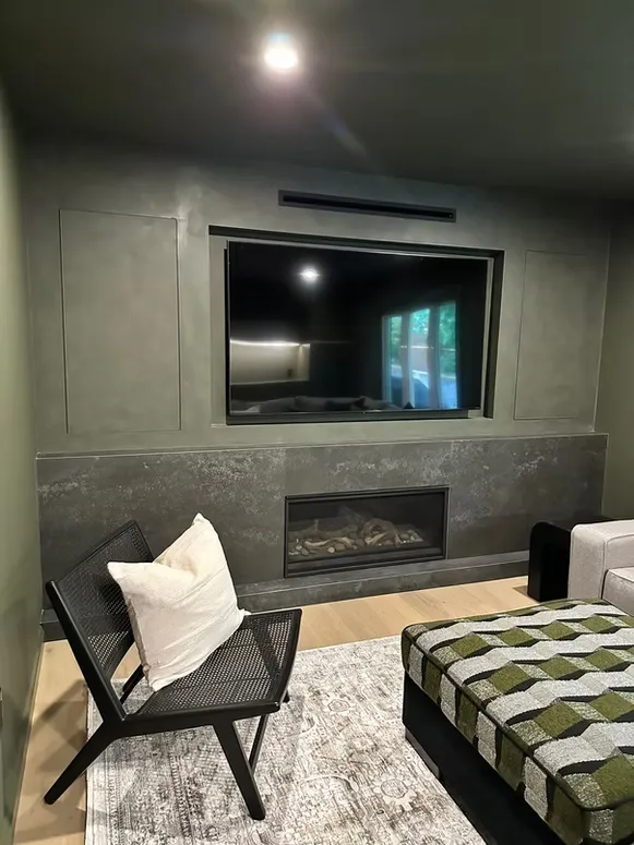 Dark green media wall with a built-in TV, a linear fireplace and a stone surround