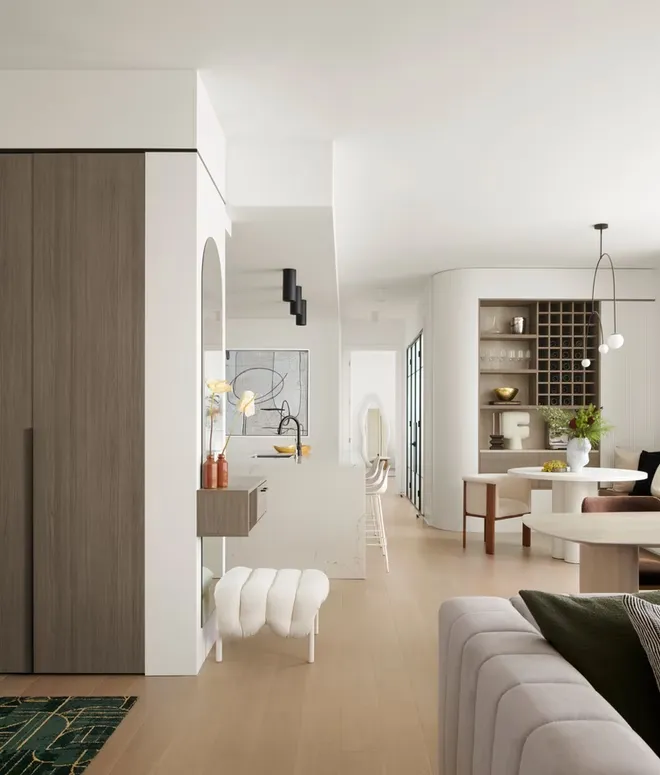 Open-plan living area with a wood-grain wardrobe tower, an arched mirror, a curved wine niche and the kitchen beyond