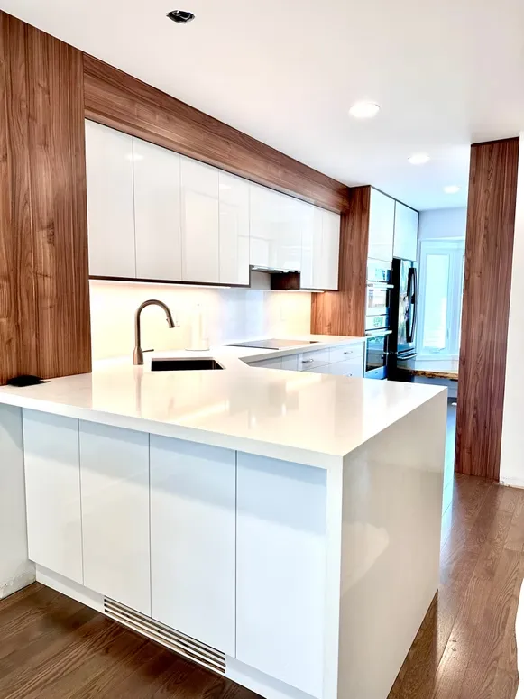 White gloss kitchen with a waterfall peninsula and walnut wall panels