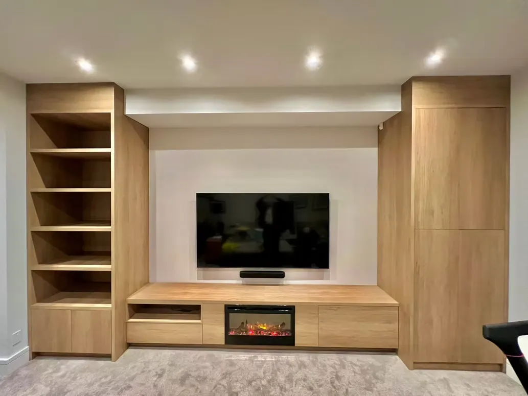 Built-in oak entertainment unit with open shelves, a TV and an electric fireplace