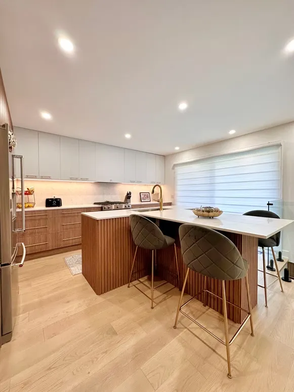 Kitchen with a fluted walnut island, quilted bar stools and white upper cabinets
