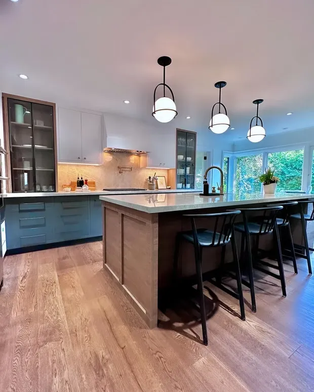 Kitchen with a wood-panelled island, three globe pendant lights and glass-front cabinets