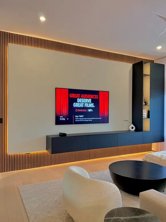 Wood slat feature wall with a floating black media console and integrated warm lighting