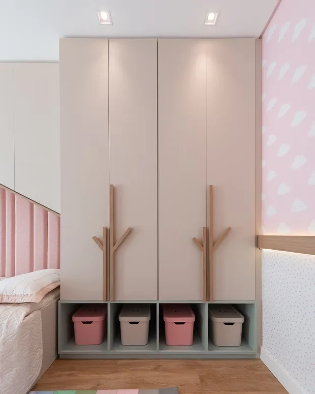 Kids wardrobe with tree-branch handles and open cubbies holding storage bins