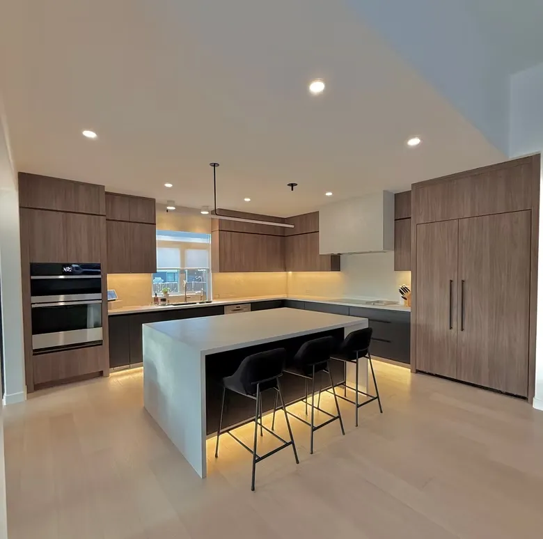 Walnut kitchen with a waterfall island, black bar stools and under-cabinet lighting