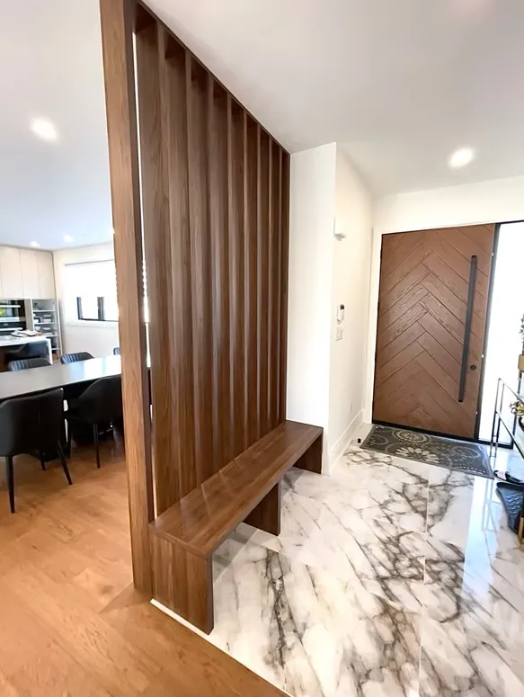 Entryway with a walnut slat divider and bench, a herringbone walnut front door and a marble floor