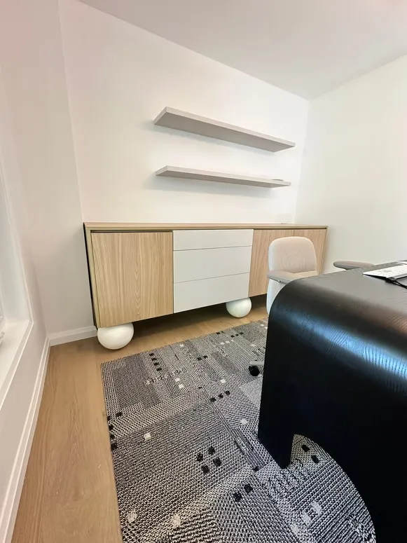 Home office with a floating oak and white credenza on round feet and two wall shelves