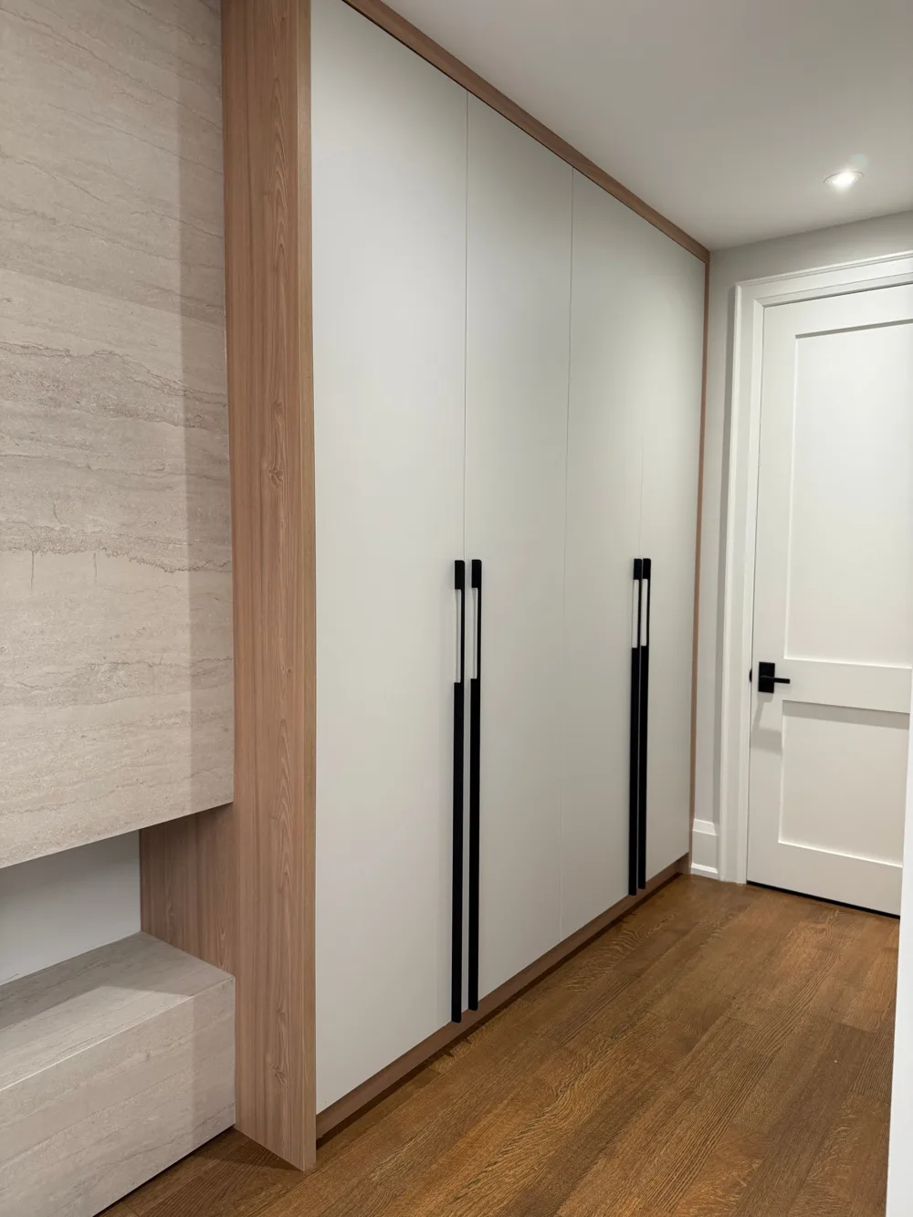 Floor-to-ceiling white closet doors with oak trim and long black pulls, installed by VIVA Cabinetry